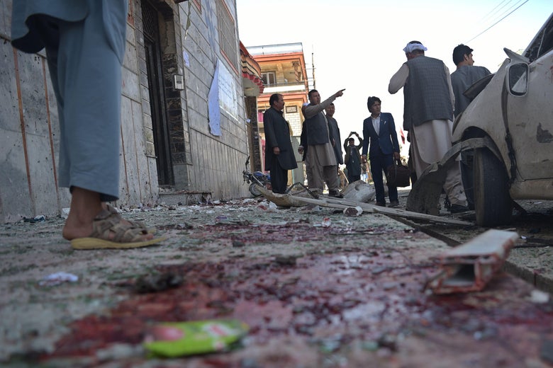 Afghan residents inspect the site of a suicide bombing outside a voter registration centre in Kabul on April 22, 2018.